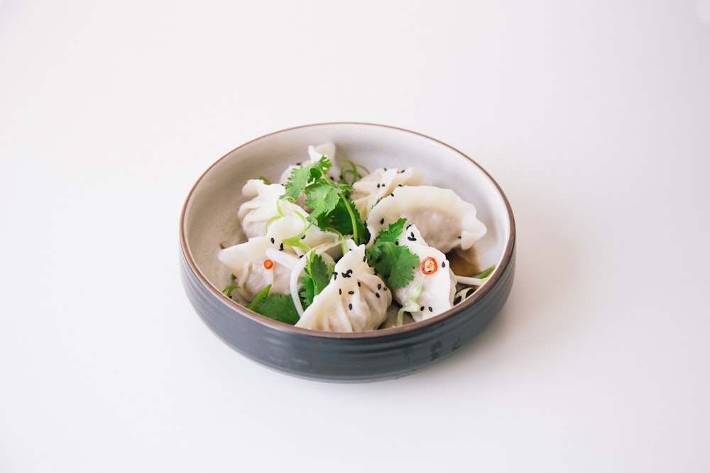 A rustic bowl of dark, glossy chicken thighs simmered in soy sauce and vinegar with whole black peppercorns and bay leaves scattered throughout.